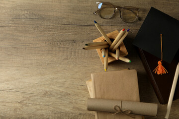 Graduate hat and books on wooden table