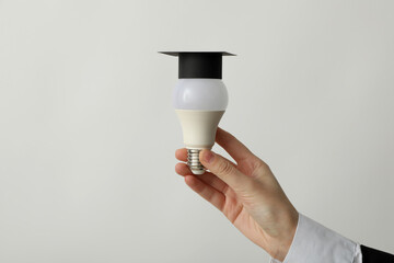 A university graduate hat on a light bulb, on a gray background.