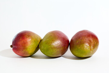 Three Ripe Mangoes Arranged Side by Side on a White Background