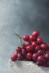 Ripe Red Grapes Bunch on a Concrete Block Against a Grey Backdrop