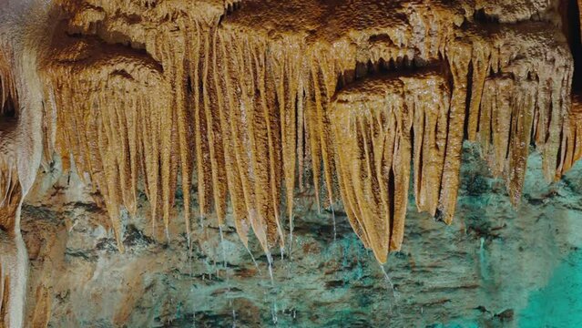 Scenic view on stalactite cave with icicle shaped formations hanging from ceiling and dripping water. Inside cavern