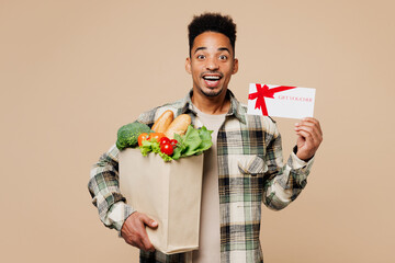 Young man wears grey shirt hold paper bag for takeaway mock up with food products gift coupon...