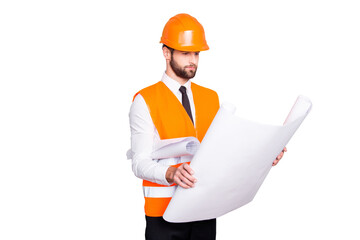 Portrait of busy handsome concentrated architect in shirt, tie and hard hat, expertising scheme of building, having open paper roll in hand, isolated on grey background