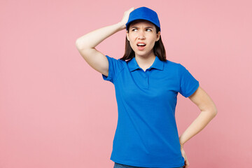 Professional delivery girl employee woman wear blue cap t-shirt uniform workwear work as dealer courier hold scratch head look aside isolated on plain pastel pink background studio. Service concept