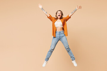 Full body young surprised shocked woman she wears orange shirt casual clothes jump high with outstretched hands look camera isolated on plain pastel light beige background studio. Lifestyle concept. - 791453944