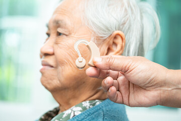 Asian senior woman patient wearing a hearing aid for treating hearing loss problem.