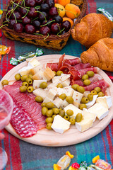 lot of various types of cheese with olives, sausages, cheese, croissants, fruits and other products. concept of picnic and relaxation