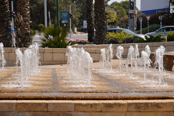Splashing fountain water a park in city, row of fountains	