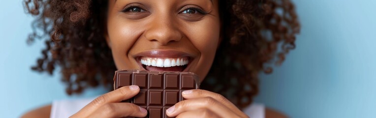 Excited African American woman holding a chocolate bar in front of her face