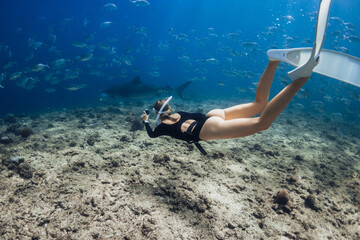 Woman dives and shooting on camera sharks underwater in the Maldives. Free diving with sharks