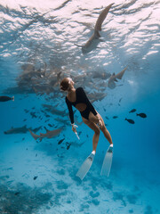 Woman freediver in a tropical water with nurse sharks in Maldives