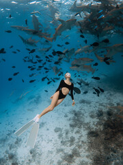 Slim woman freediver in tropical water with nurse sharks