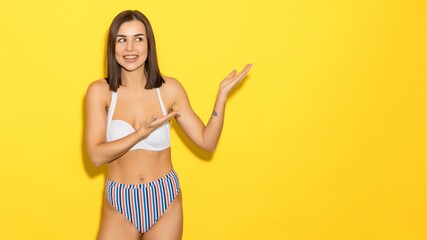 Summer vacation. Luxury resort. A young woman in a swimsuit on a yellow background. Mockup,...