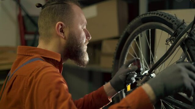 Bike mechanic adjust derailleur on wheel, oiling and repair bicycle in workshop. Bicycle maintenance and repair