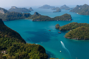 Boats navigate the serene blue waters among lush green islands under a clear sky. Koh Samui Island, Thailand