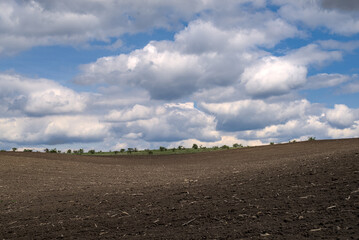 Photo of plowed field and sky with clouds