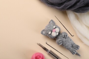 Felted cat, wool and tools on beige table, flat lay. Space for text - obrazy, fototapety, plakaty
