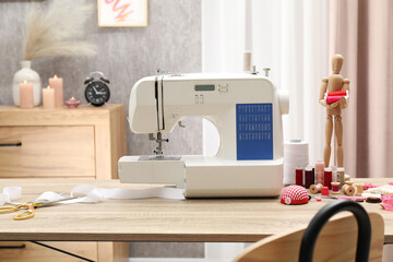 White sewing machine, cloth, craft accessories and mannequin on wooden table indoors