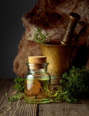 Bottle of thyme essential oil with fresh thyme twigs.
