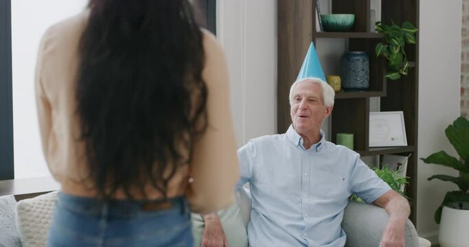 Senior man, birthday and woman with cake in living room with candles for wish, hug or celebration at home. Happy mature male person blowing out desert for party, event or surprise on sofa at house