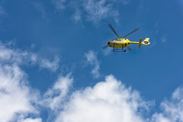 yellow ambulance helicopter flies high in the sky
