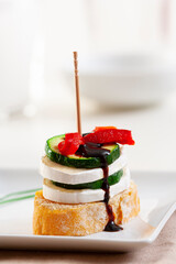 Pintxo or Basque pincho. Delicious Spanish tapa with slice of goat cheese with zucchini and red pepper...