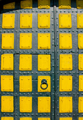 Old black door with yellow decorations. Black and yellow wooden door..