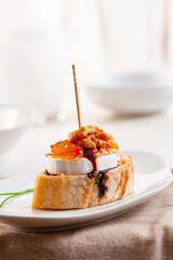 Pintxo or Basque pincho. Delicious Spanish tapa with slice of goat cheese with apricot and walnut jam...
