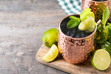 Moscow mule cocktail served with ice and lime slice on wooden table. Copy space