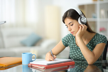 Student with headphone listening audio guide and taking notes
