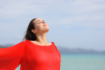 Woman in red breathing and relaxing on the beach