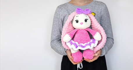 Woman with bunny. Holding a soft bunny toy. Girl with a toy. Bunny. Long ears. Hobby crochet. Handmade. Amigurumi. Pink knitted rabbit. Soft toy.   Crocheting of soft toys