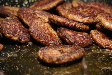 Beef burger patties sizzling on a hot  pan.