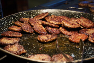 Beef burger patties sizzling on a hot  pan.
