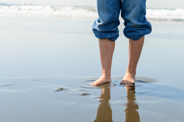 波打ち際を裸足で歩く女性
