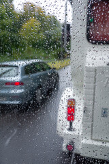 Blick auf eine befahrene Verkehrsstraße durch eine Fensterscheibe bei Regenwetter