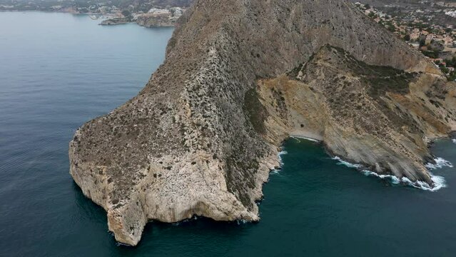 Drone is flying along the shore of Calpe, Spain, massive mountain, landmark, 4k