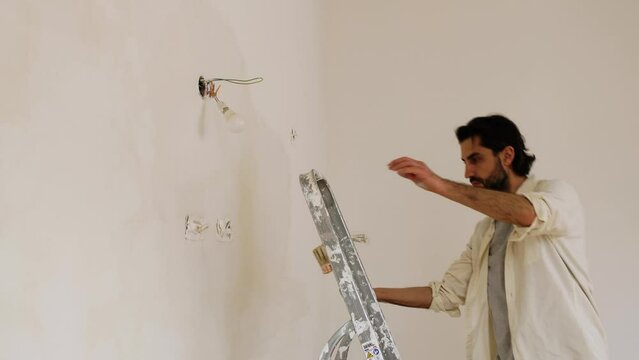 A Man With A Large Brush Applying Limewash Paint On The Wall. Static Shot
