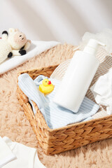 Fototapeta na wymiar Template for baby bath accessories advertising, a rattan basket contains products for baby bath, a rubber duck, a blue striped towel and a blank label bottle. Top view photo, copy space