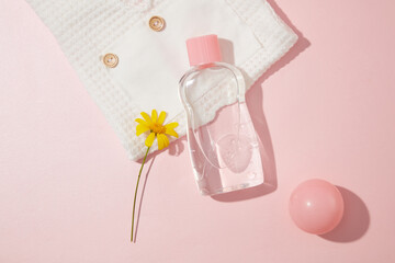Layout for advertising products take care baby body and skin over light pink background, a bottle without label with transparent liquid in center. Flat lay style, top view