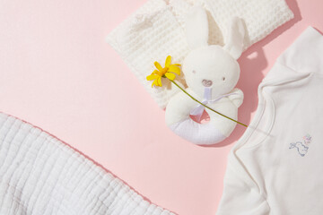 Baby care accessories minimalist style against pastel pink background, top view photo with a daisy flower as an accent. Copy space for text or adding elements