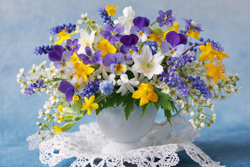 Bouquet of wild spring flowers in a cup, blue muscari, hepatica, pansies, yellow anemones, white bird cherry. Beautiful card - 791521944