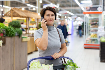 Elderly woman talking on mobile phone in supermarket