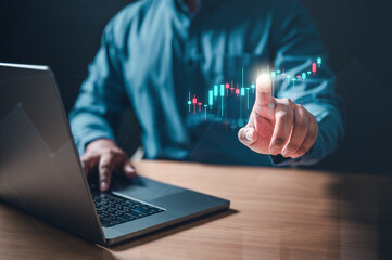graph, broker, candlestick, chart, index, invest, marketing, multi, growth, statistic. A man is using a laptop computer and pointing at a graph. The graph is showing a stock market trend.