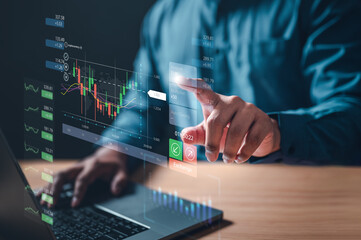 chart, graph, index, invest, management, multi, statistic, trend, profit, strategy. A man is using a laptop to make a trade in the stock market. He is pointing at a green button on the screen.
