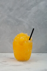 Refreshing Citrus Granizado or Orange iced slushie drink in glass with drinking straw. Sweet fruit...