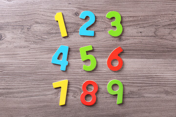 Colorful numbers on wooden school desk, flat lay