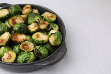 Delicious roasted Brussels sprouts in baking dish on light table, closeup. Space for text