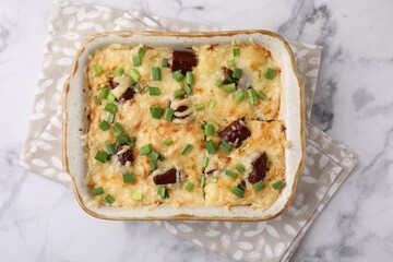 Tasty sausage casserole in baking dish on white marble table, top view