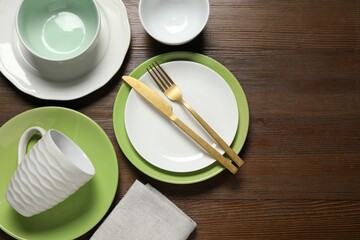 Beautiful ceramic dishware, cup and cutlery on wooden table, flat lay. Space for text